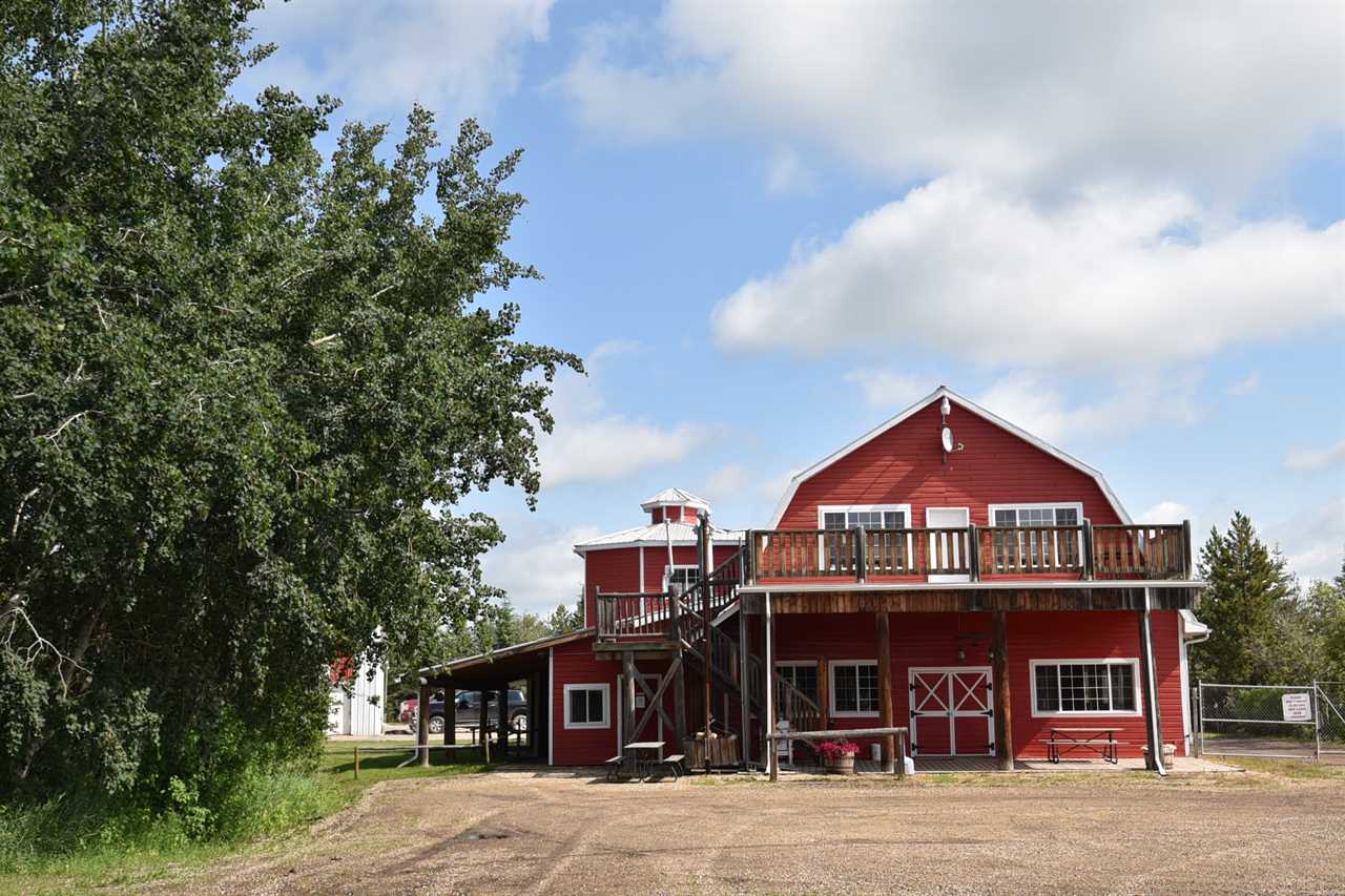 An old barn with windows and balcony on second floor.