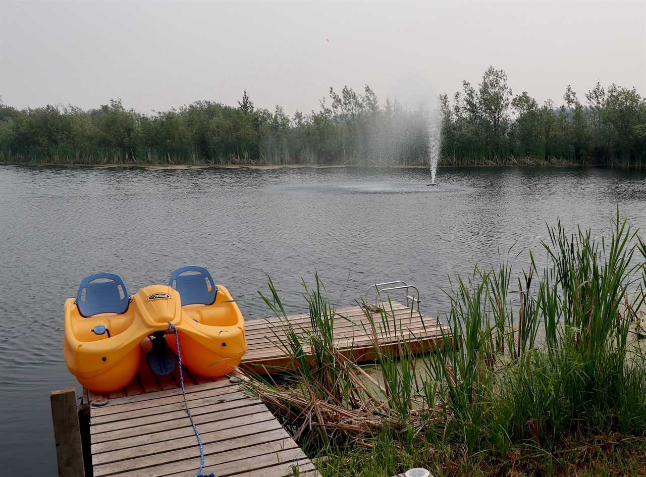 Lone paddleboat on a dock with fountain gushing over a pond in the background.