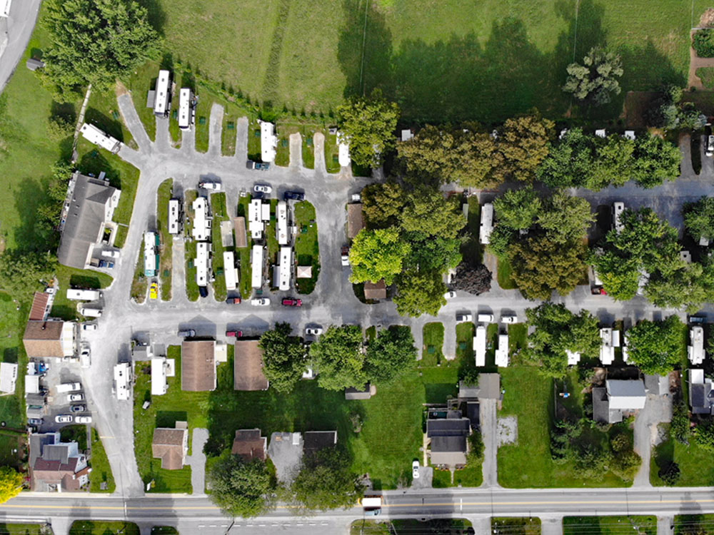 An aerial shot of an RV park set in a lush, green, rustic area.