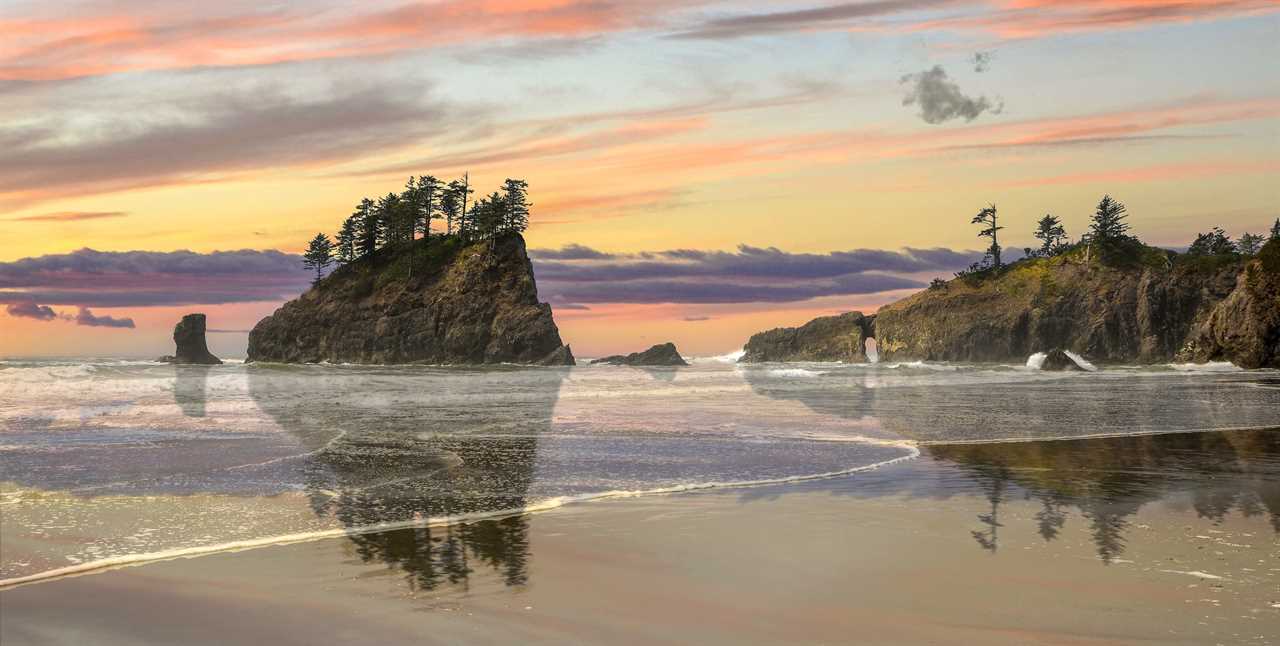 Sunset over a glassy shoreline with rock outcroppings in the distance.