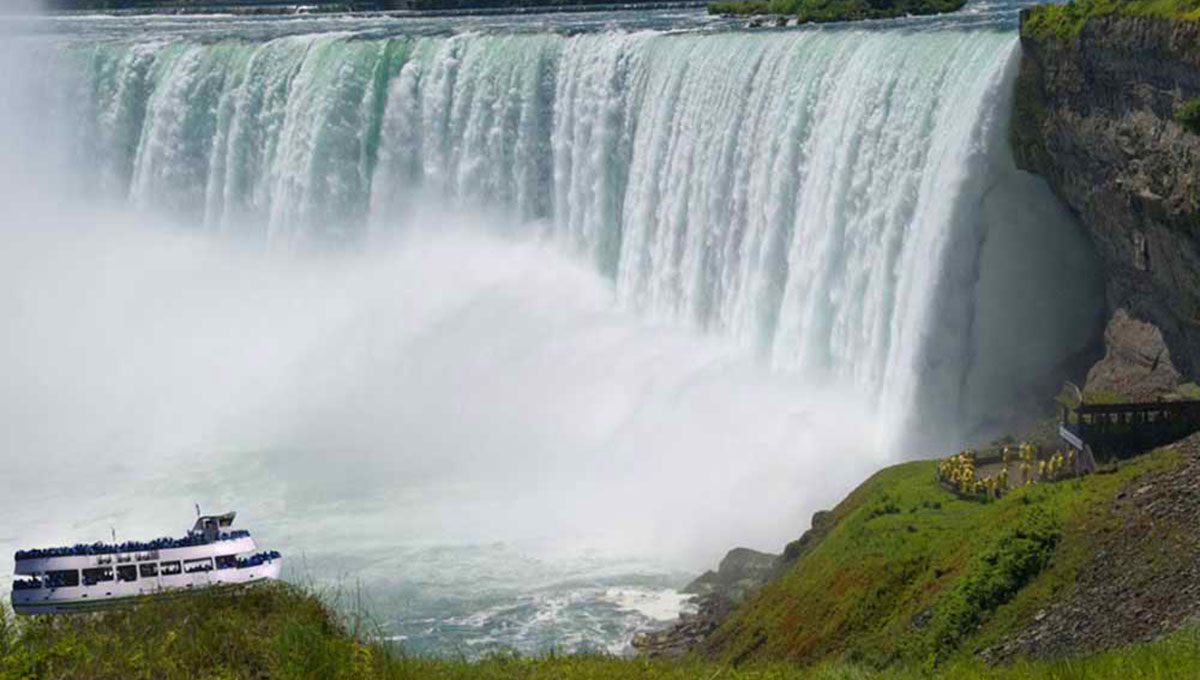 A curtain of water falls thunders near a tour boat.