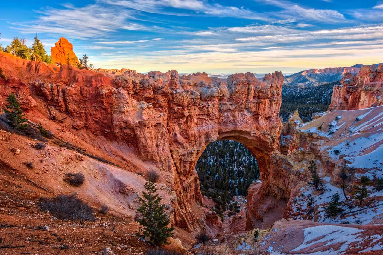 A rock arch under a cobalt blue sky accented with cotton clouds.