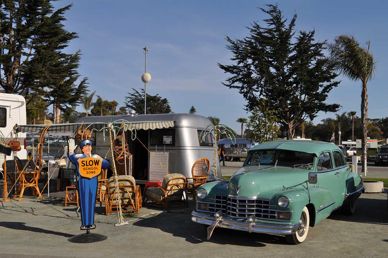 Green vintage sedan with boxy trailer.