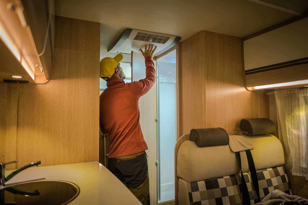 Man adjusting air conditioning unit in RV.