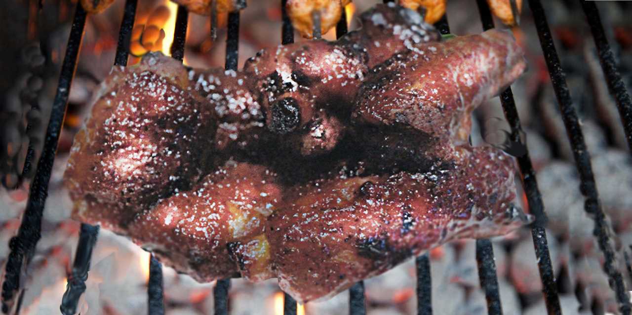 Brushed with barbecue sauce, a clutch of ribs cook on the grill.