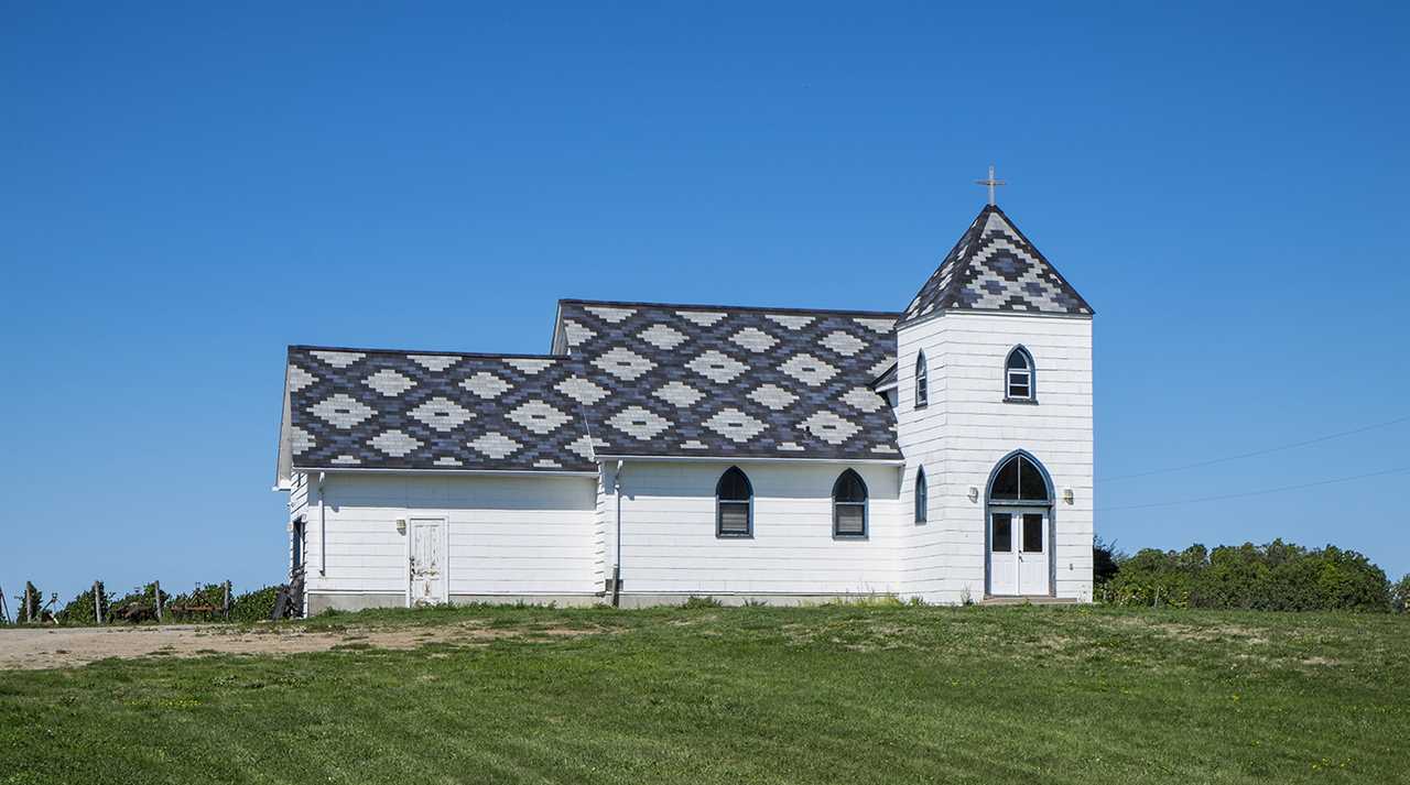 Church building on a green grassy landscape.