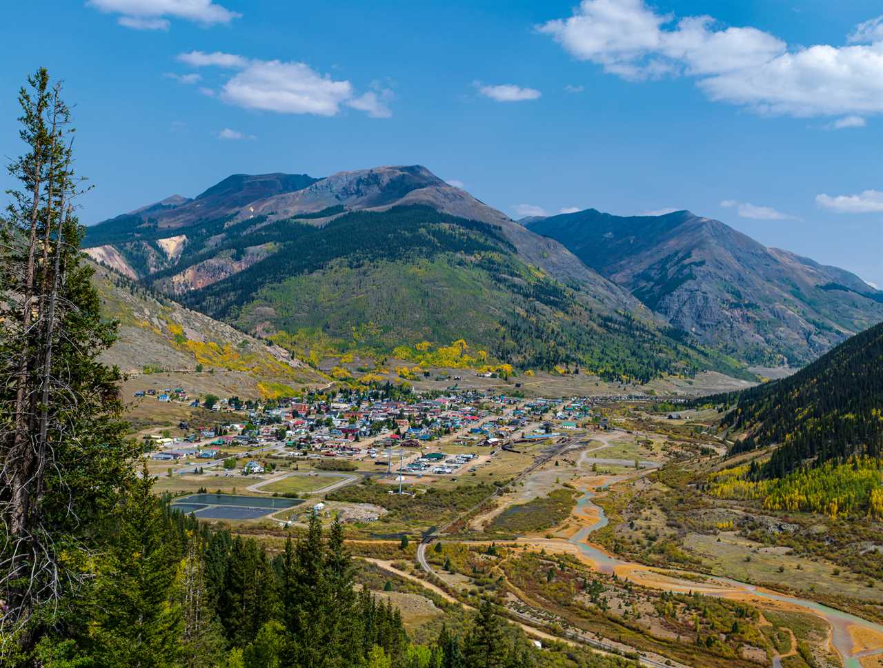 View of small town from high elevation amid high mountain peaks.