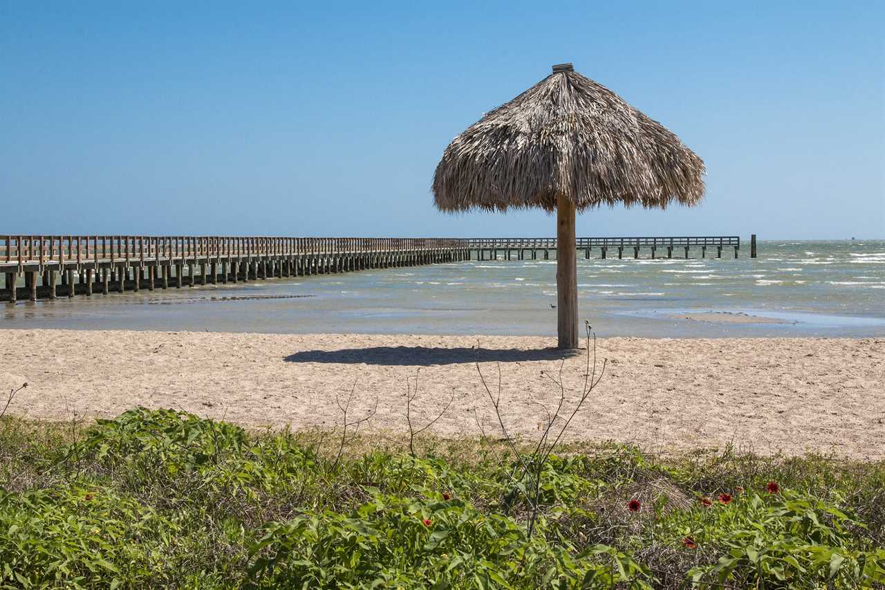 Pier with thatched beach umbrella.