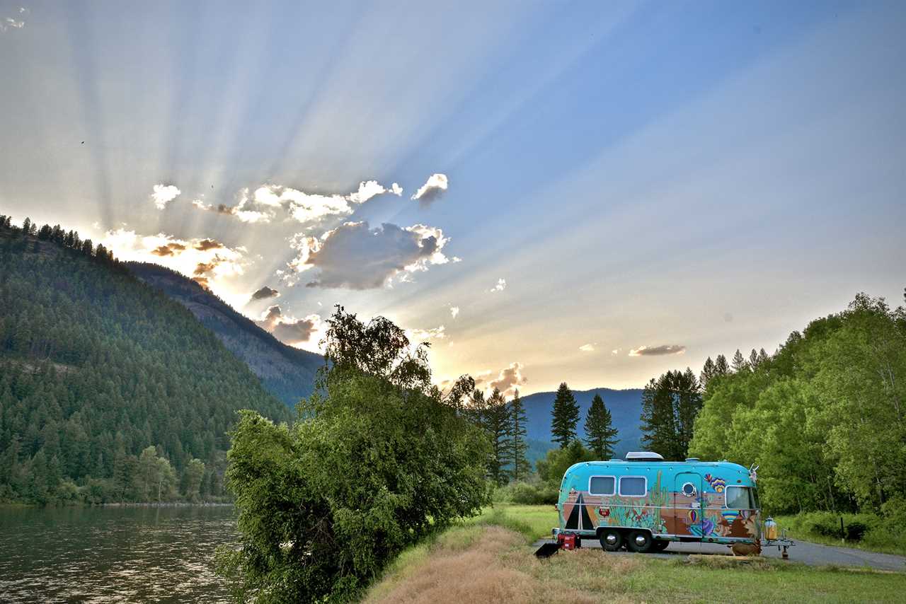 Trailer parked near river during sunset.