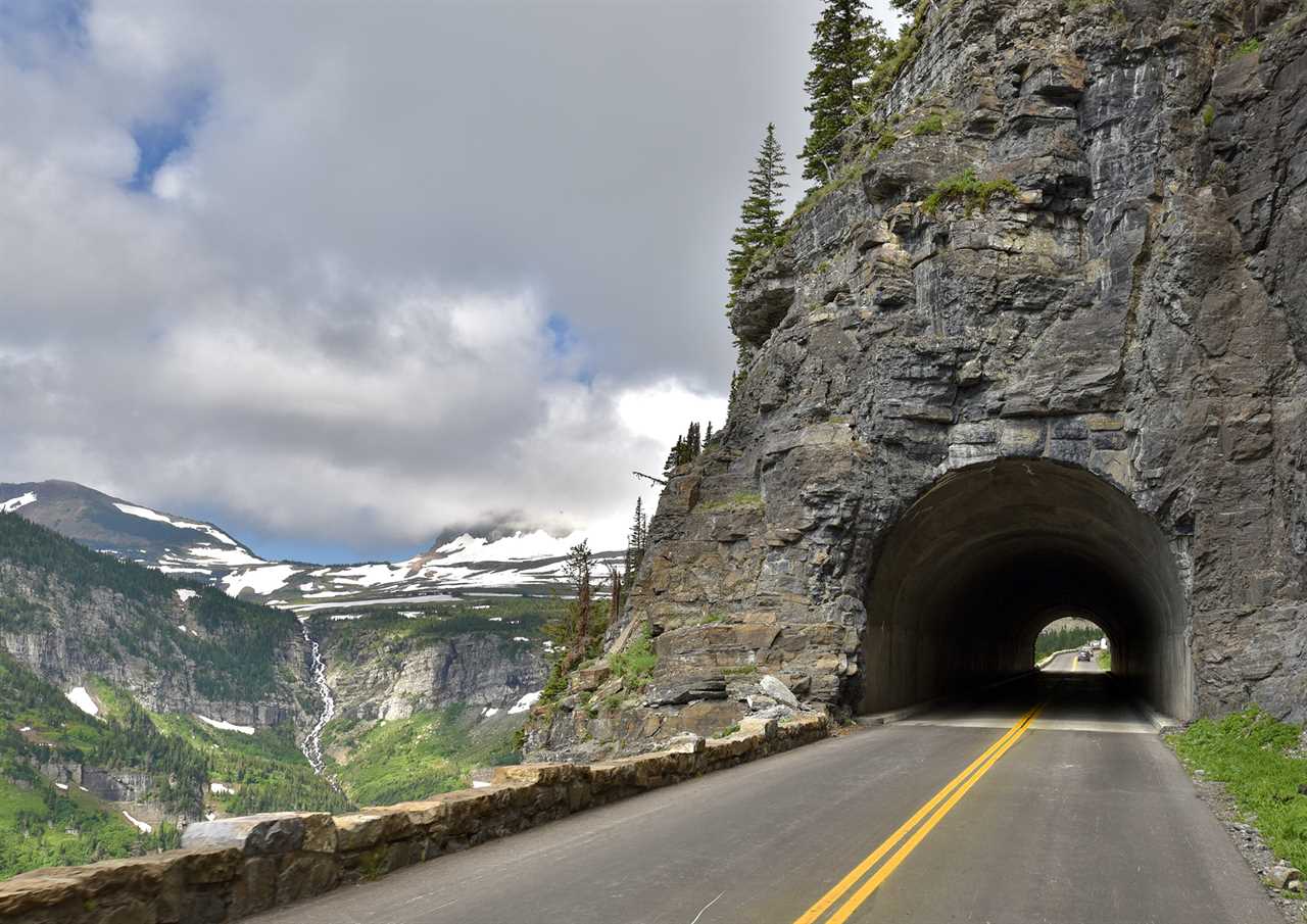 A tunnel cuts through a mountain on a road climbing an alpine slope. 