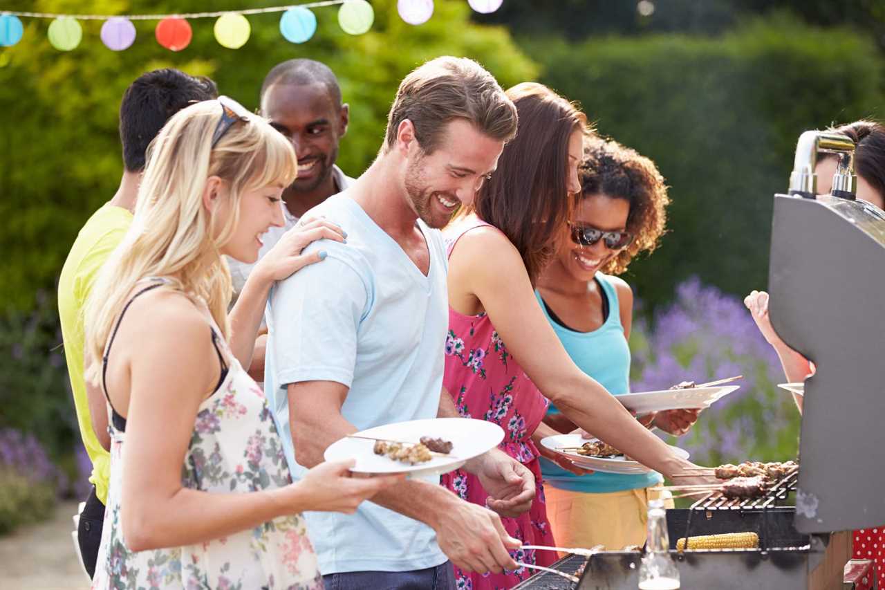 Group Of Friends Having Outdoor Barbeque At Home In Garden