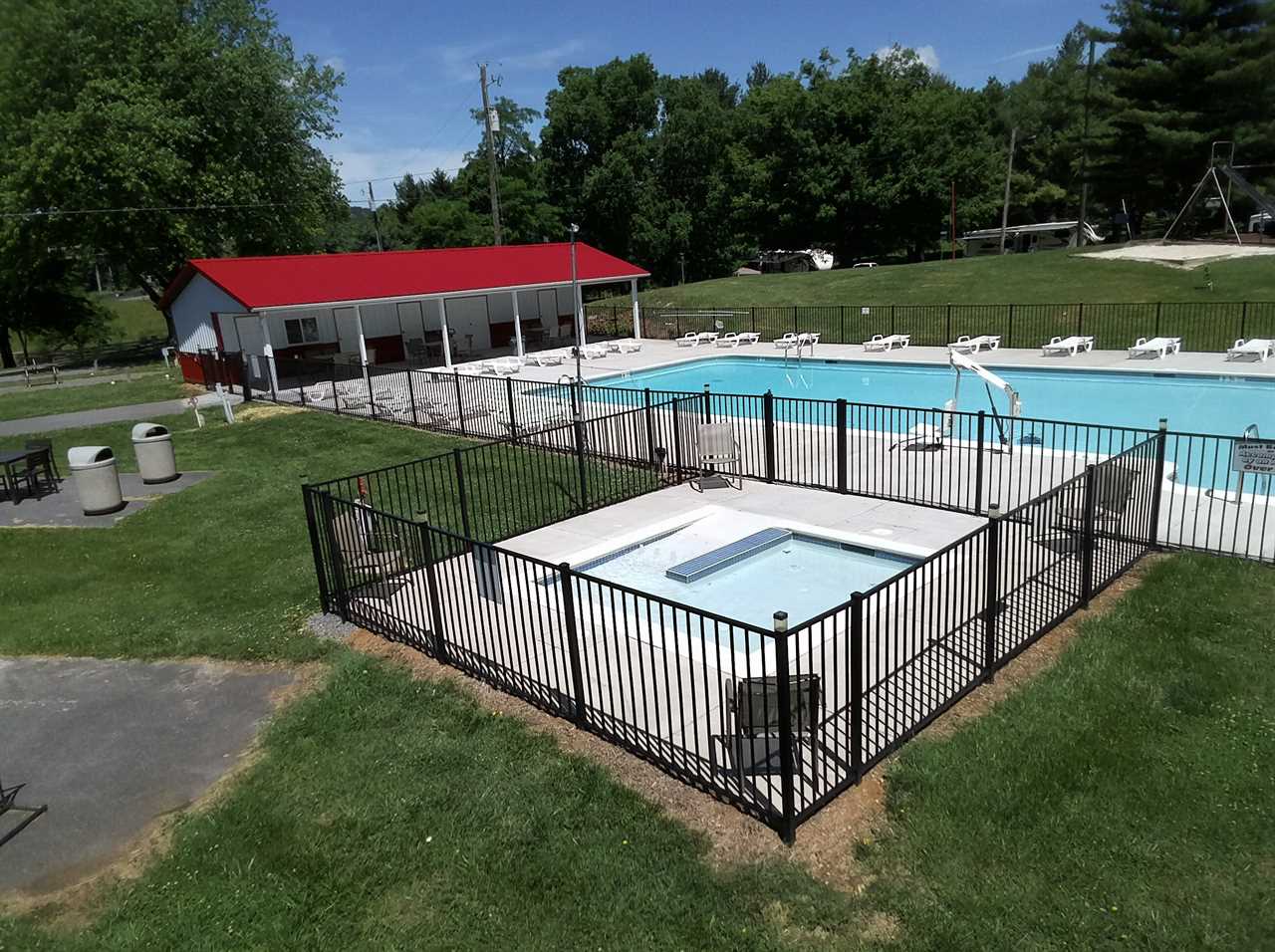 A square swimming pool with adjacent hot tub.