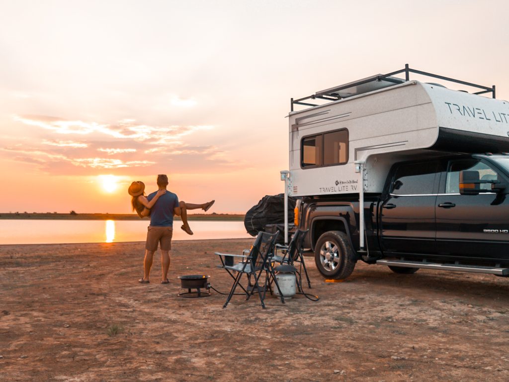 couple enjoying lake sunset with truck camper.