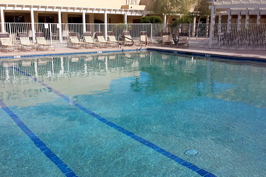 A large square pool with lanes on the floor made of tile.