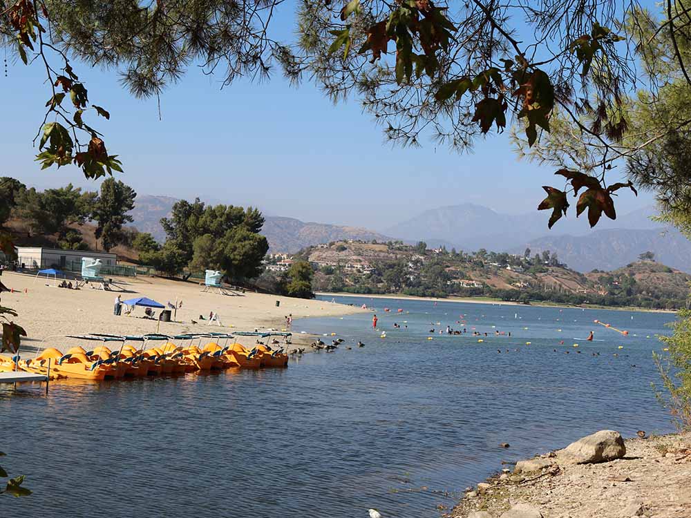 A sand beach surrounds a lake as bathers and boaters play on the water. 