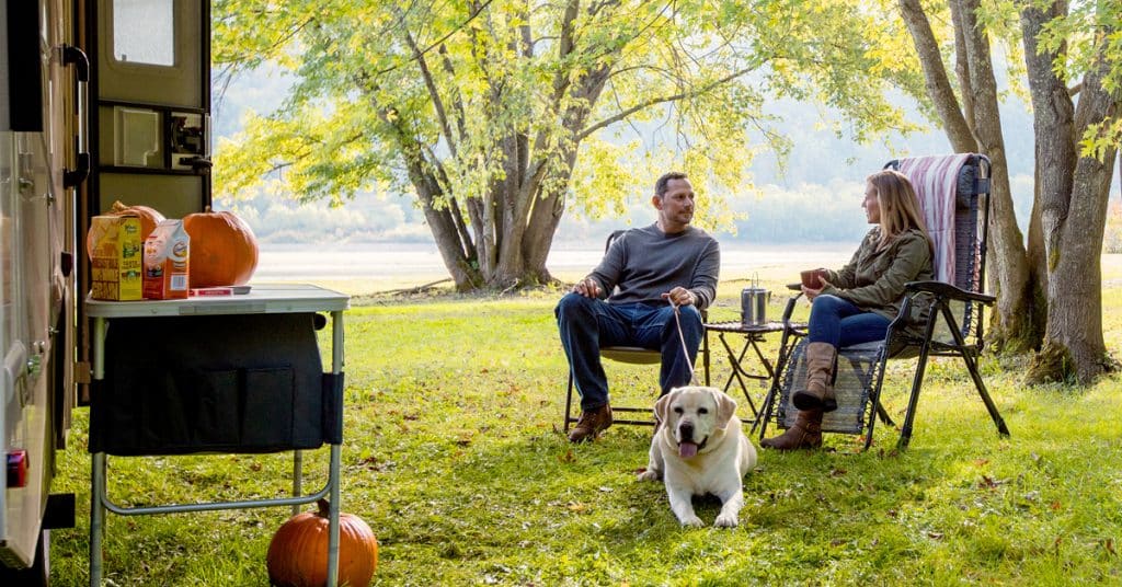 A couple enjoying some comfortable chairs outside their RV on a sunny day