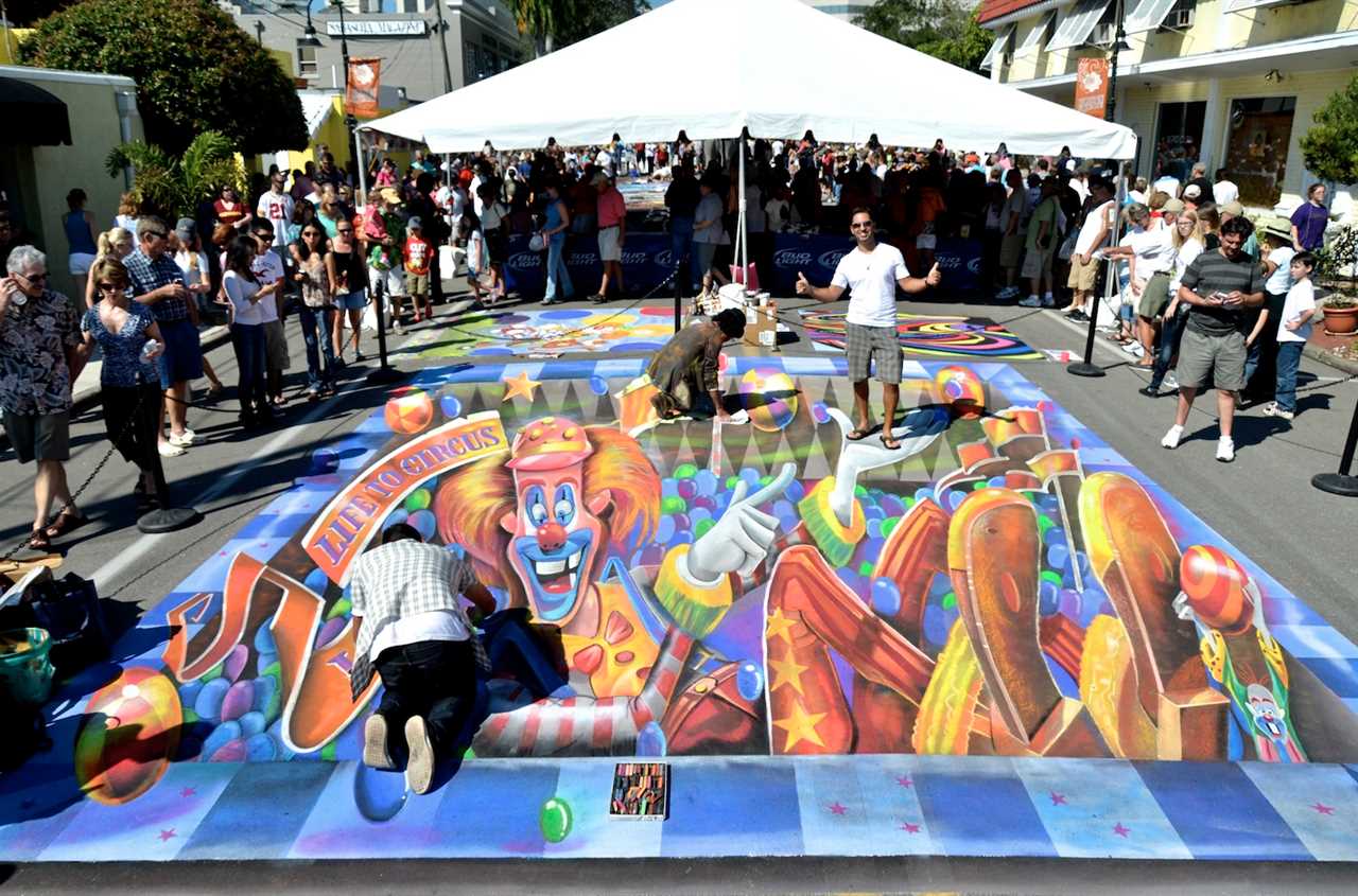 Man draws chalk picture of a clow on the street.