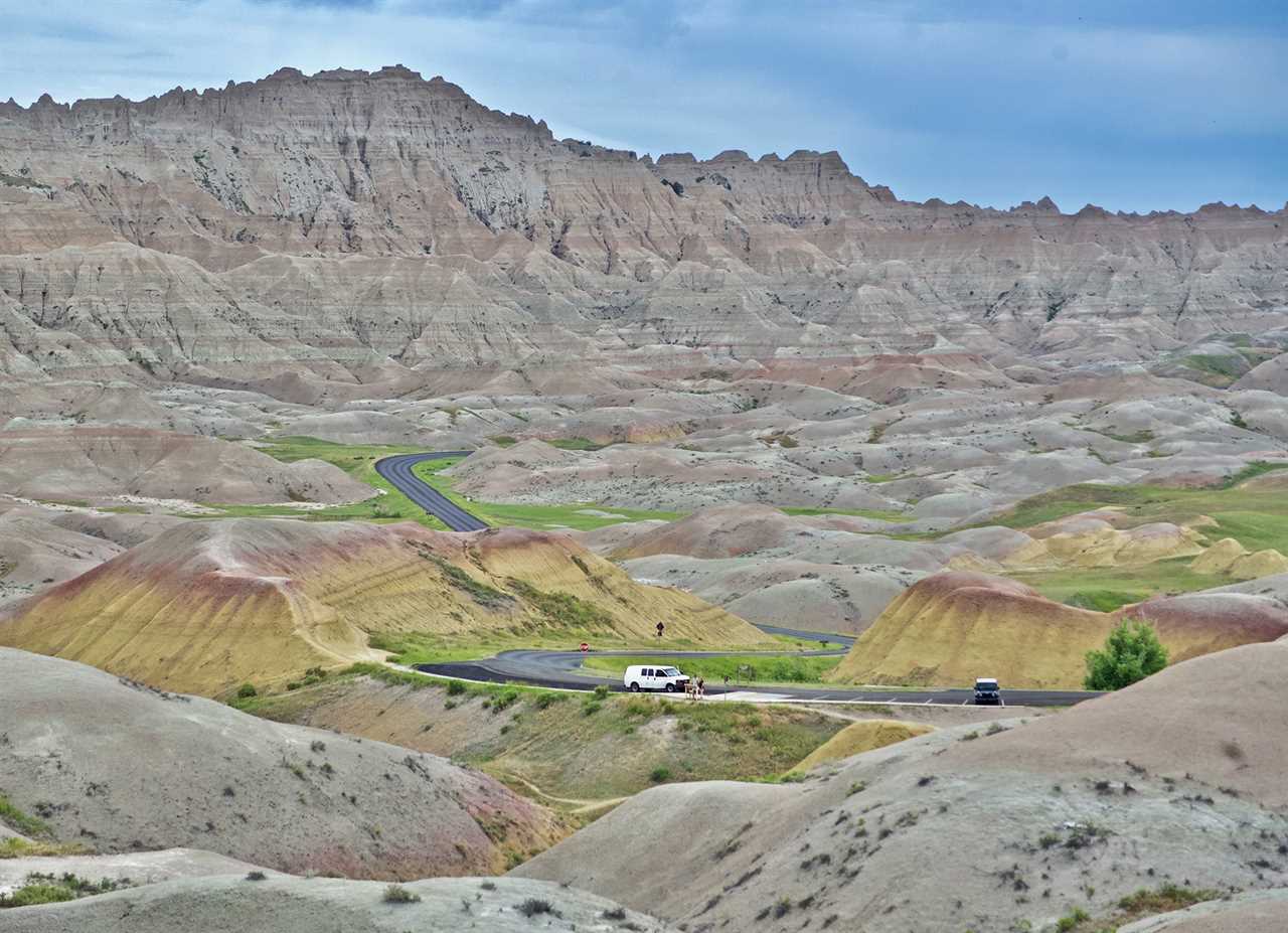 A white SUV on a winding highway between rugged hills.