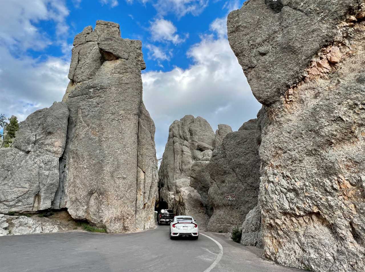 Cars enter a steep chasm formed by needle-like rocks on each side of the highway.