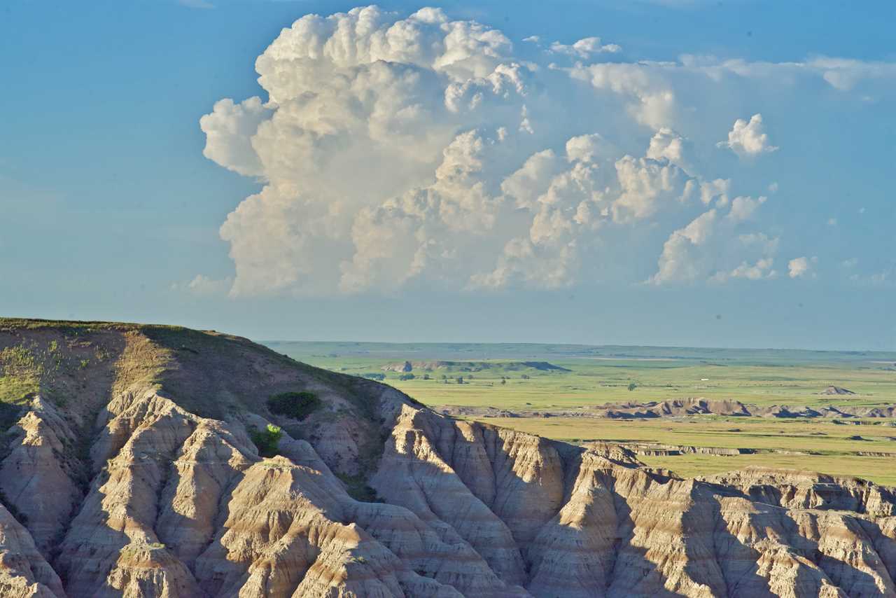 A huge, towering cloud looms above a prairie