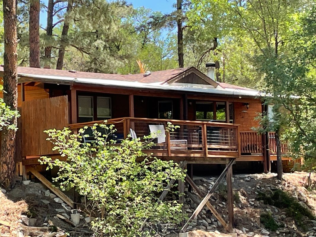 A house with balcony perched on a bluff surrounded by trees