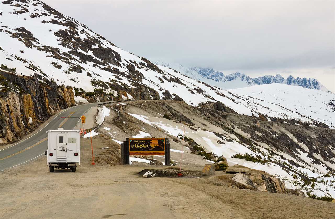 RV About to tackle incline hugging a snowy ridge.