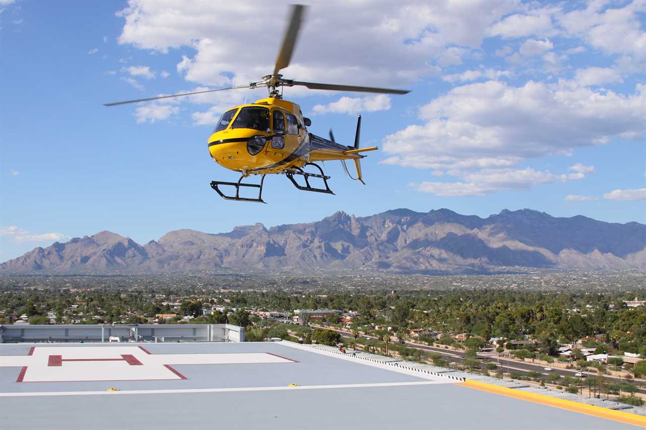 A yellow rescue helicopter lands on a hospital landing pad.
