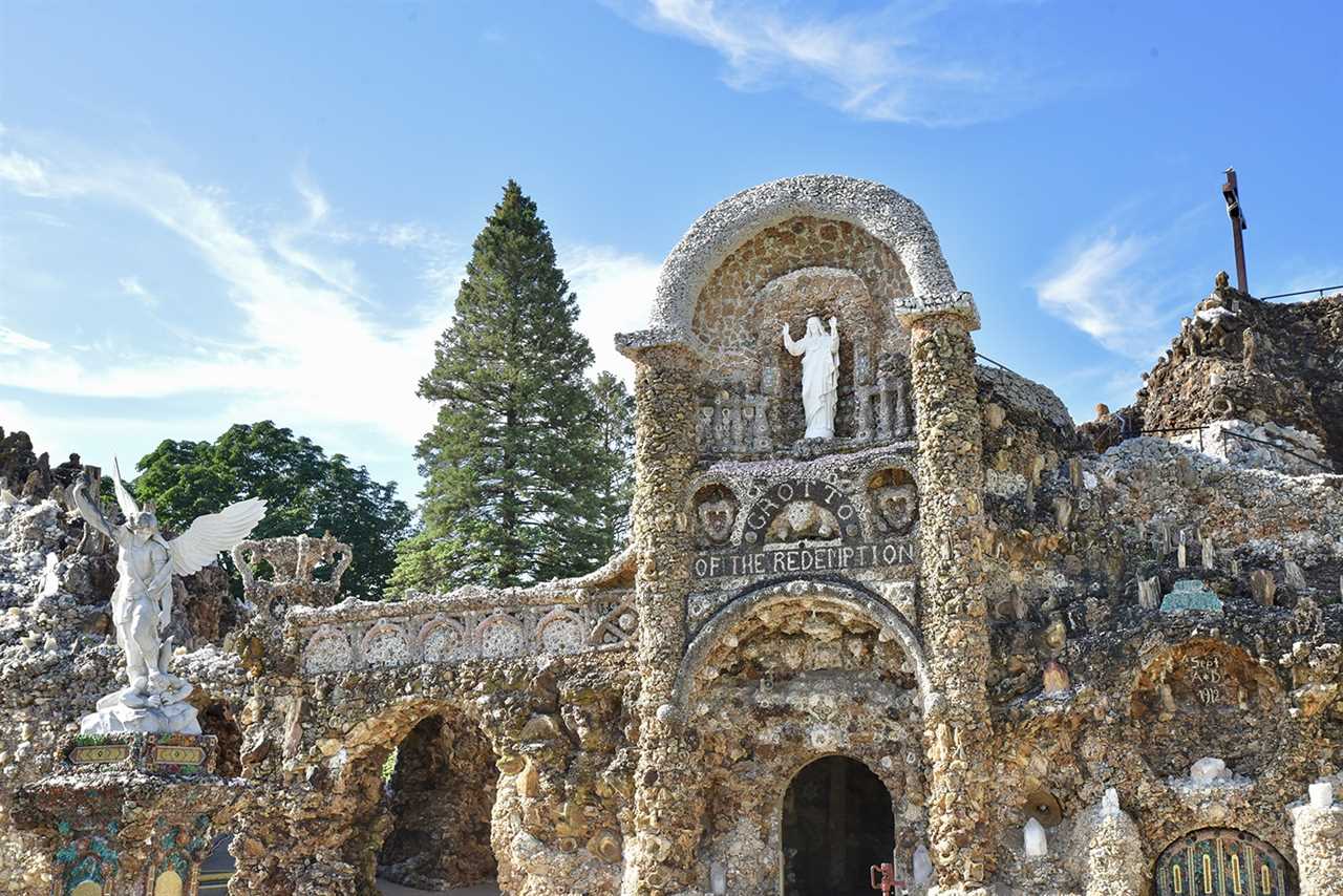 Closer view of white statue with arms upraised in a grotto.