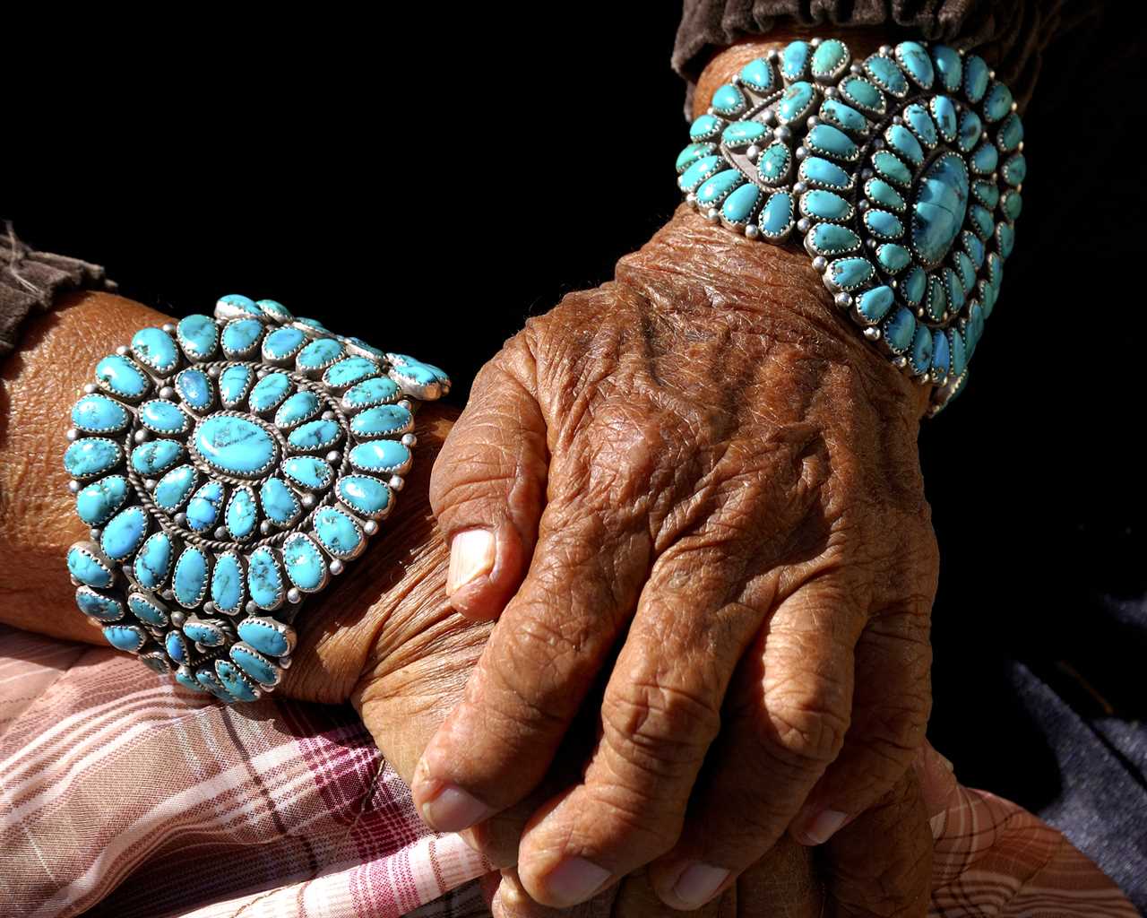 Woman with bracelets adorned with turquoise gems.