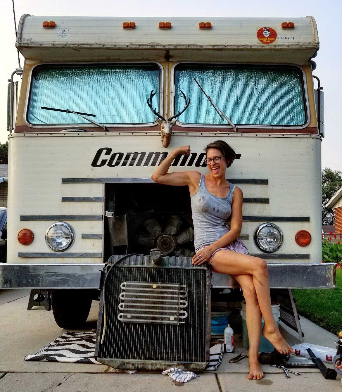 A woman sits on a motorhome bumper with a radiator.