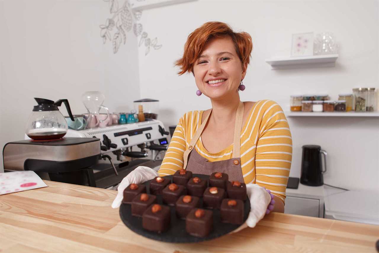 Woman presents a tray filled with chocolate confections.