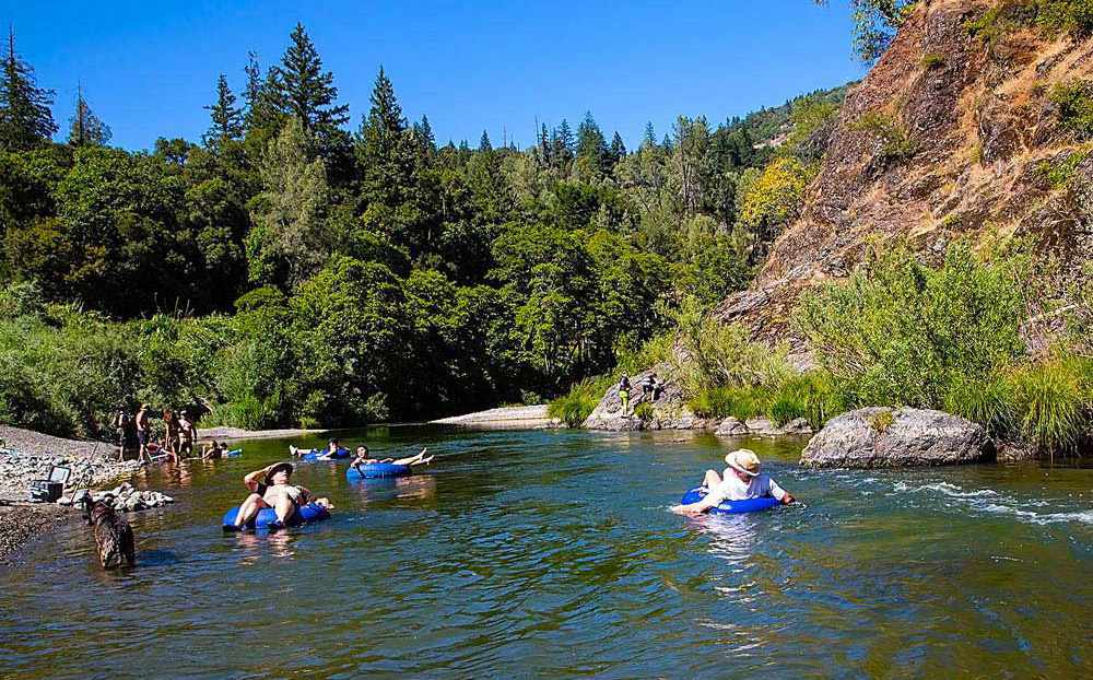 Leisure seekers float on a river on inner tubes.
