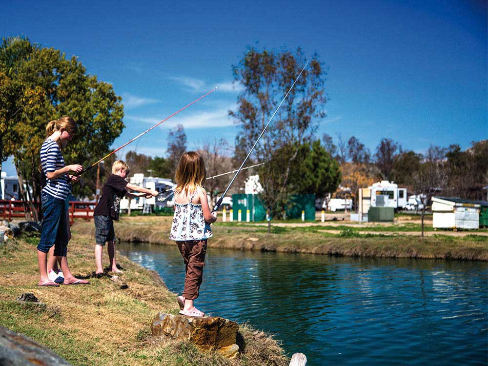 three kids fishing in a canal