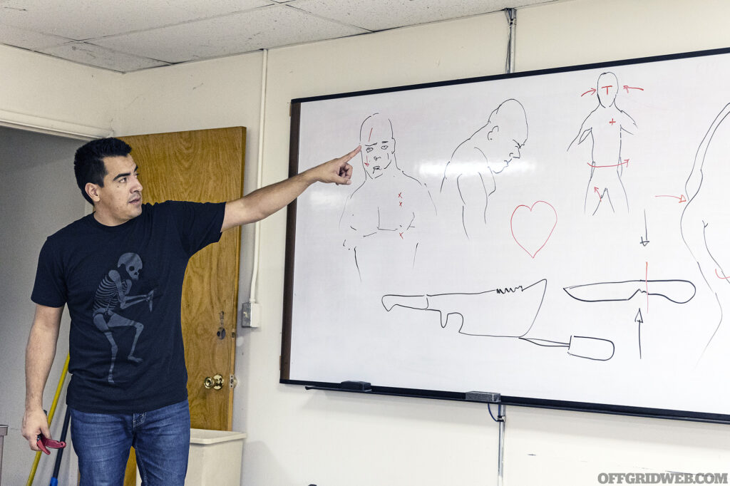 Instructor Ed Calderon using drawings on a whiteboard to highlight vulnerable areas on human bodies.
