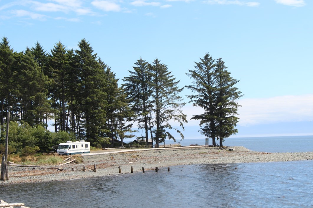 A lone RV parked on a beach with trees