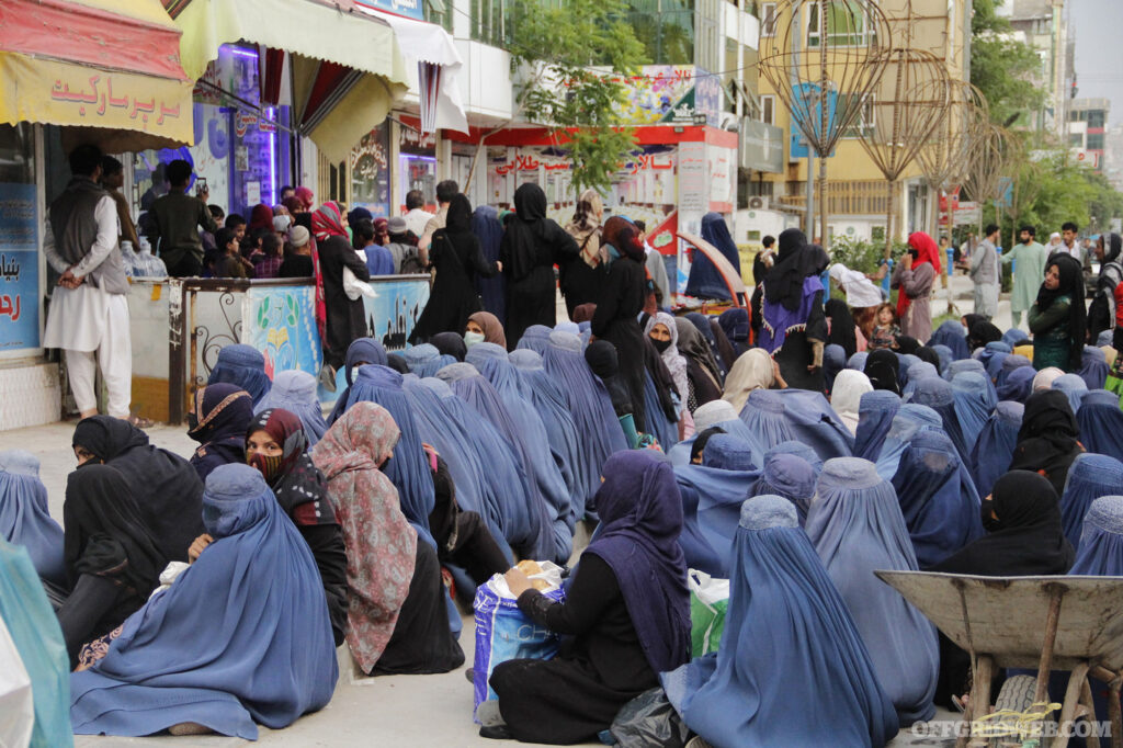 Several Afghan women sit outside a supermarket waiting for bread to feed their families.