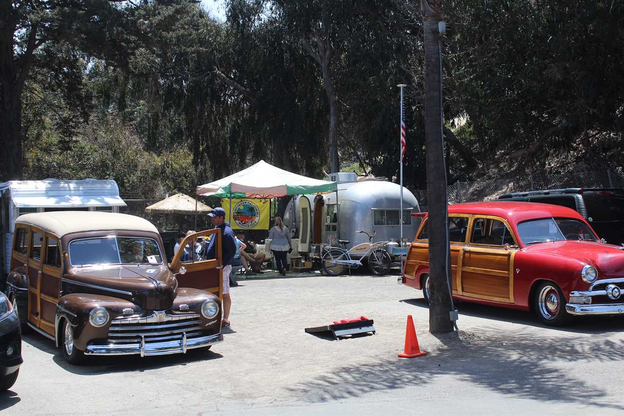 Two classic station wagons with a silver bullet trailer.