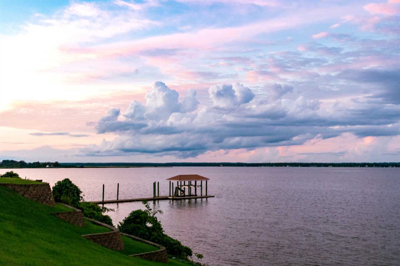 Sun sets over wide river with lone fishing dock.