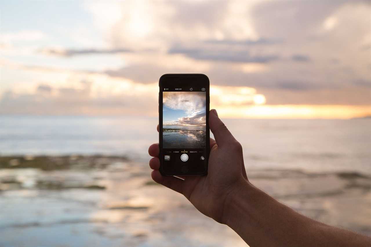 Smart phone held up against sky.