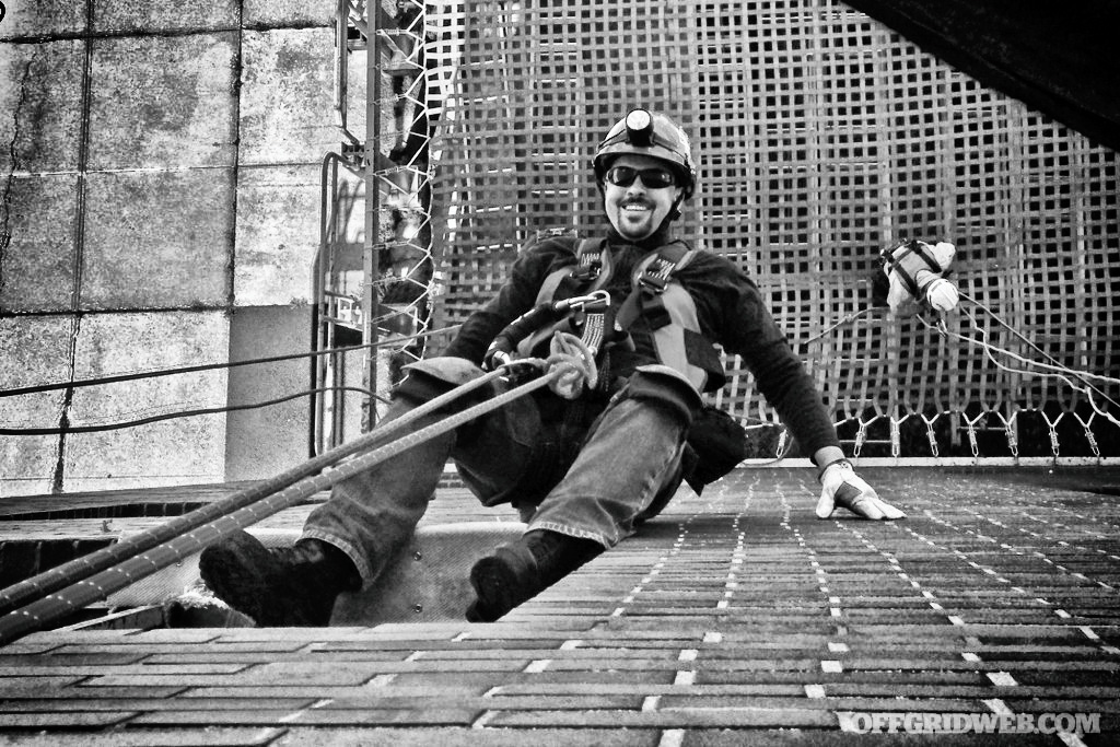 Black and white photo ofJoey Nickischer belaying down an recreational climbing wall.