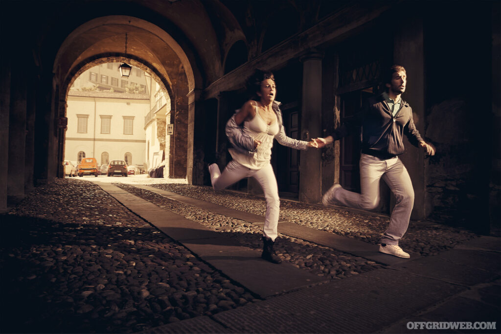 Sepia photo of a couple running through an ominous street tunnel in small town of northern Italy as if someone bad was chasing them. If they could try to be cool, they may experience a better outcome.