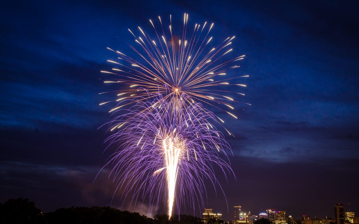 Fireworks over river with dark lavender blue sky