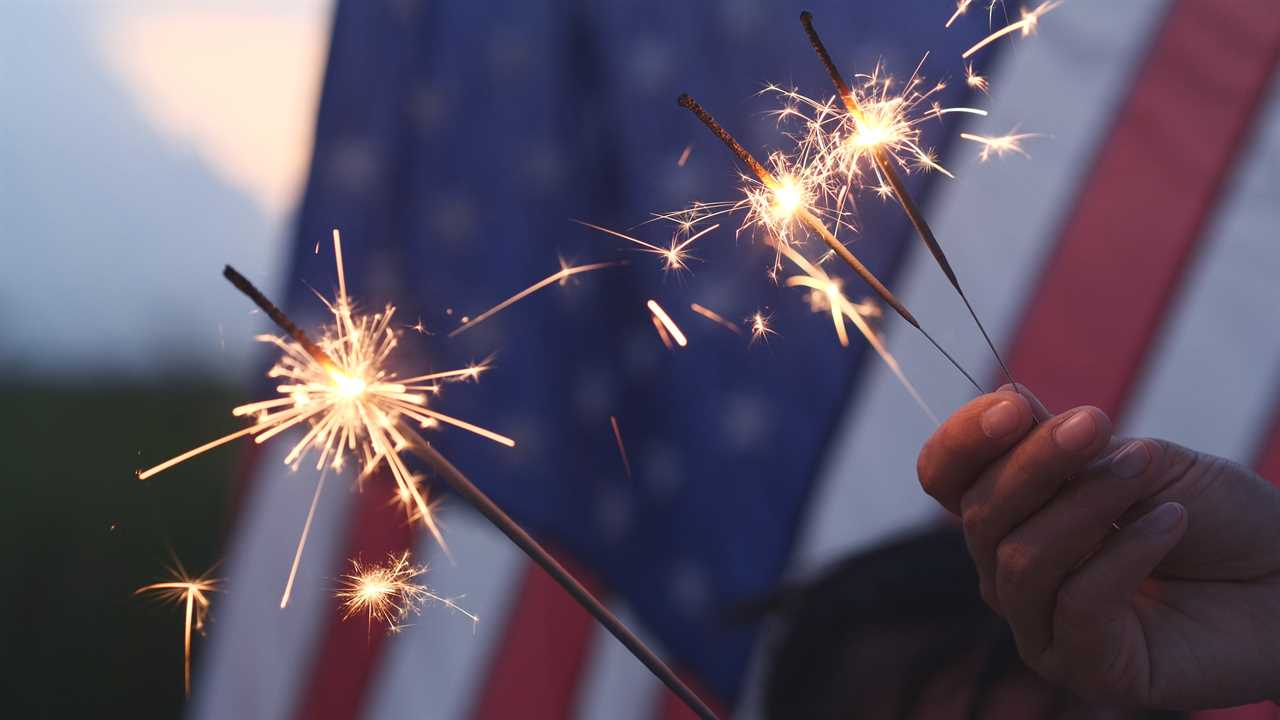 Holding sparklers against a U.S. Flag background.