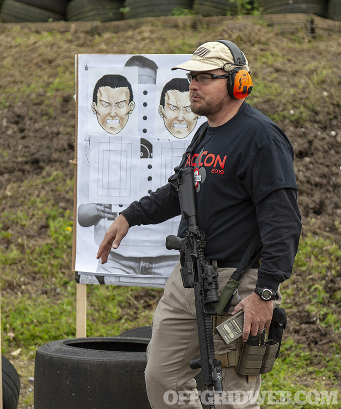 Photo of John Hearne standing in front of a target at a firing range.