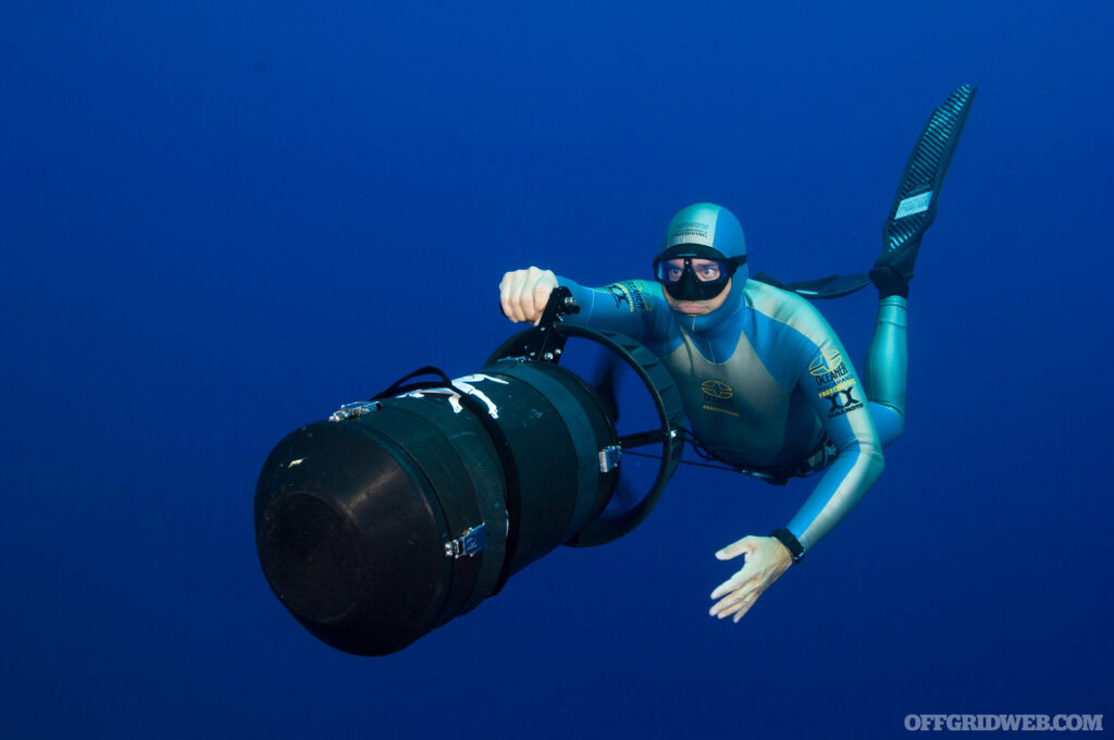 Photo of a diver practicing survival breathing and operating a sea scooter underwater.