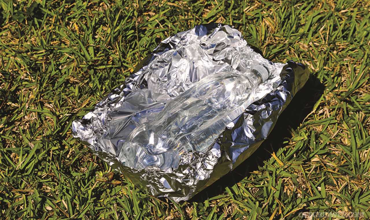 A photo of a clear bottle filled with water resting on a sheet of aluminum foil in the sun as a water purification method.