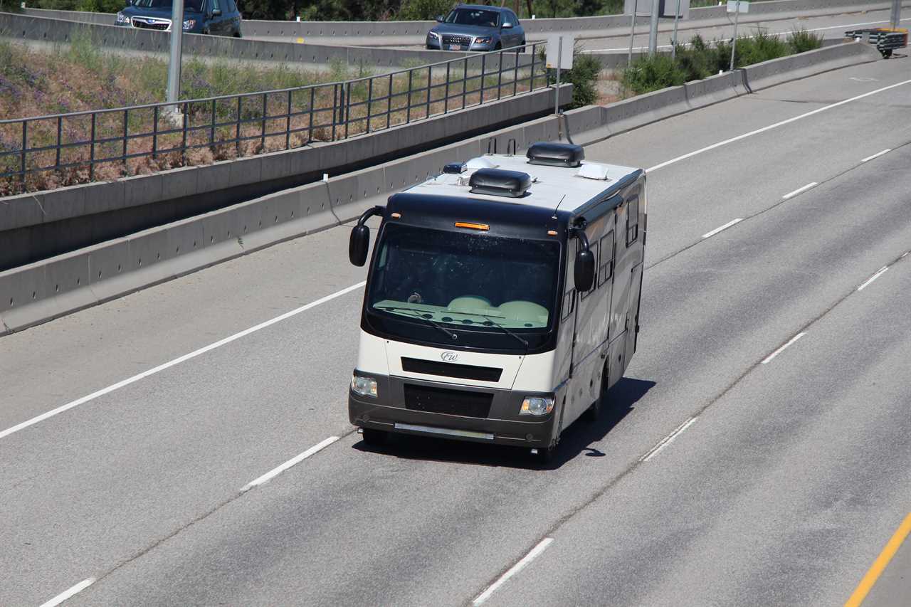 RV driving on highway, pair of AC units on the roof.