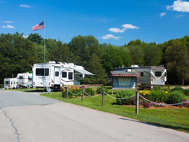 Fifth-wheel against American flag and blue sky.