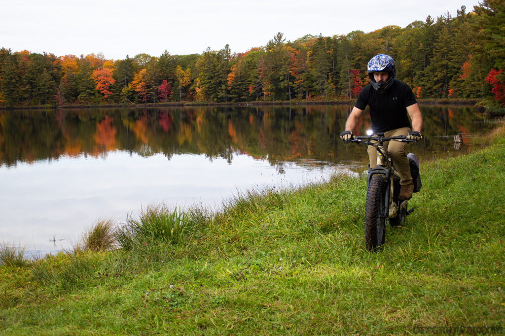 Photo of an adult male riding an eBike off the trail near a remote campsite in Michigan's Upper Peninsula.