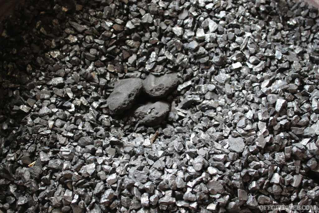 Photo of a small pile of charcoal briquettes lying on a bed of mineral coal.